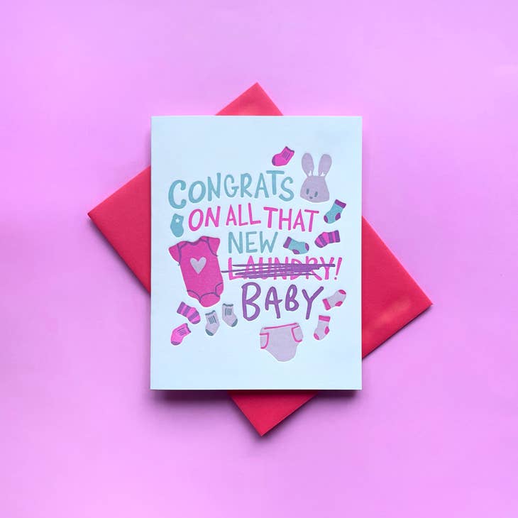 White background with images of purple and pink bunnies, socks and diapers. Blue and pink text says, "Congrats on all that new  laundry, baby". A red envelope is included. 