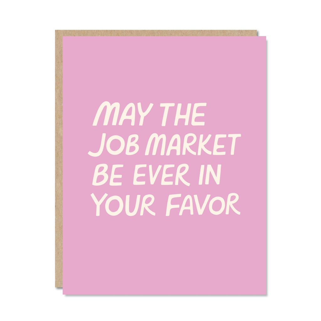 Greeting card with pink background and white text says, "May the job market be ever in your favor". Kraft envelope included. 