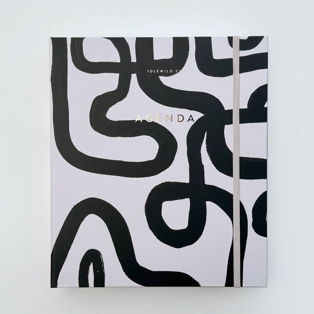 Image of cover of planner with white background with black squiggles and gold foil text says, "Agenda". 