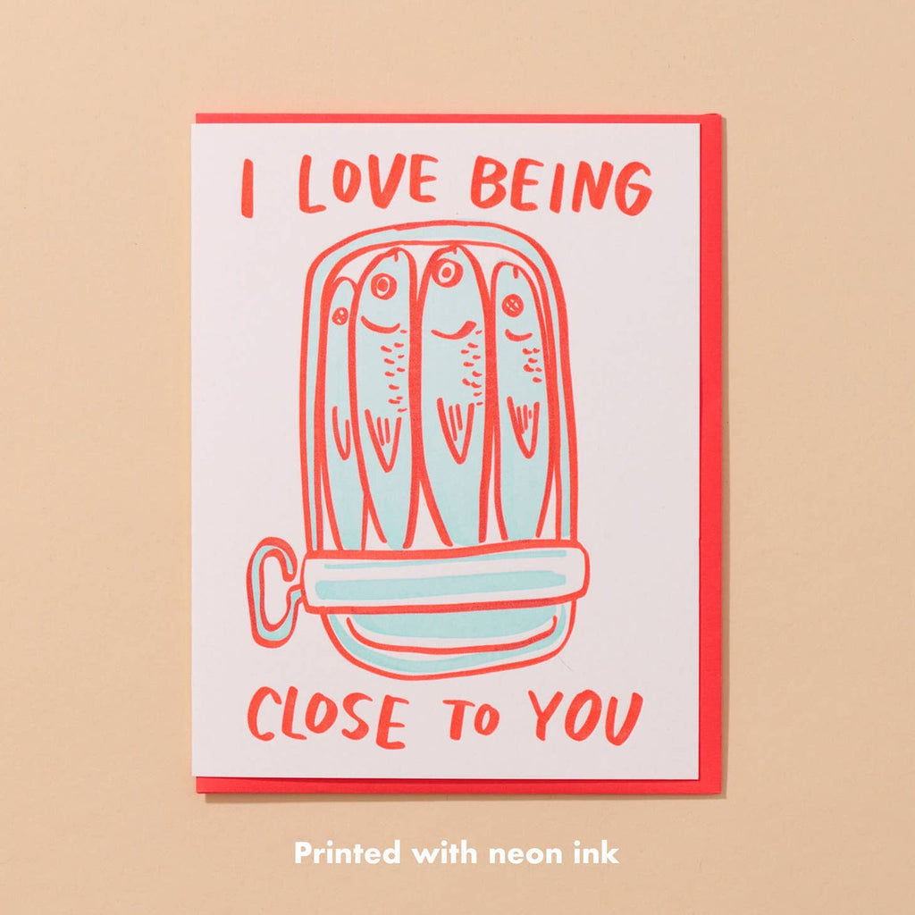 Greeting card with white background and image of a can of sardines in light blue with red text says, "I love being close to you". Red envelope included. 