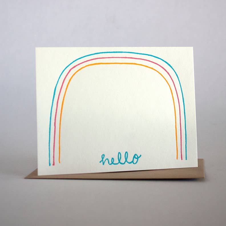 White background with image of line rainbow in blue, pink and yellow with blue text says, “hello”. Kraft envelopes are included. 