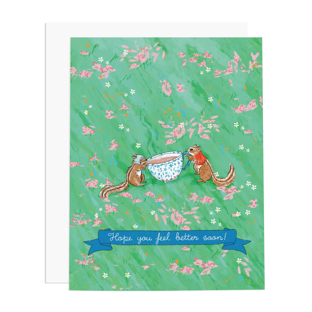 Greeting card with green background with pink flowers and an image of two chipmunks holding and sipping from a tea cup with a blue banner with white text says, "Hope you feel better soon!". White envelop included. 