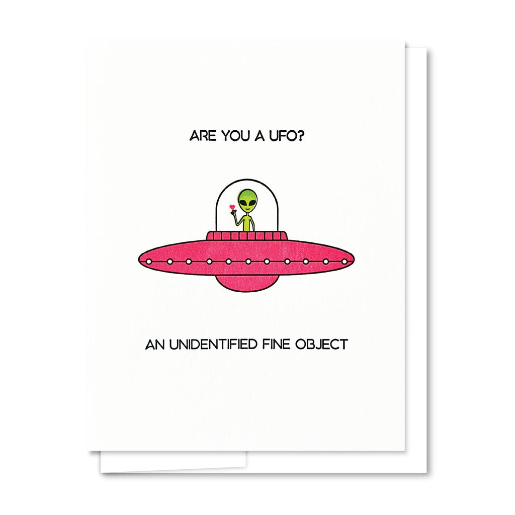 Greeting card with white background and image of a green alien inside a red spaceship with black text says, "Are you a UFO? An unidentified fine object". White envelope included. 