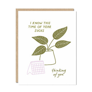White background with image of a plant and calendar with olive green text says, "I know this time of year sucks" and "thinking of you". Kraft envelope included. 