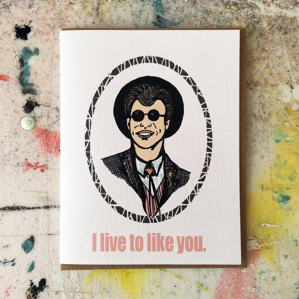 White background with images of Duckie from Pretty in Pink in black, tan and pink with pink text says, "I live to like you.". Kraft envelope included. 