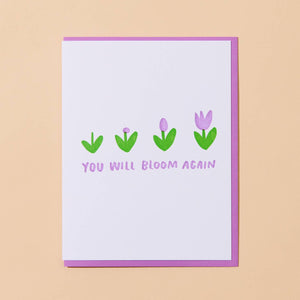 Greeting card with white background  and images of four flowers in stages of blooming with pink text says, "You will bloom again". Bright pink envelope included.