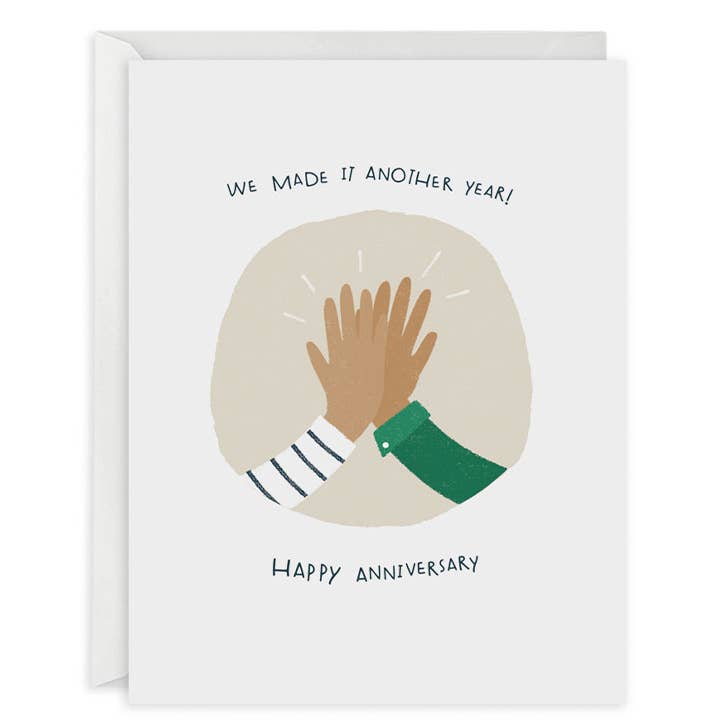 Greeting card with white background and image of two hands doing a high five with black text says, "We made it another year!, Happy Anniversary". White envelope included. 