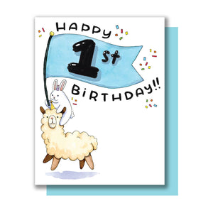 White background with image of a bunny riding on a llama holding a blue banner with a “1st” on it. Black text says “Happy birthday”. Blue envelope is included. 
