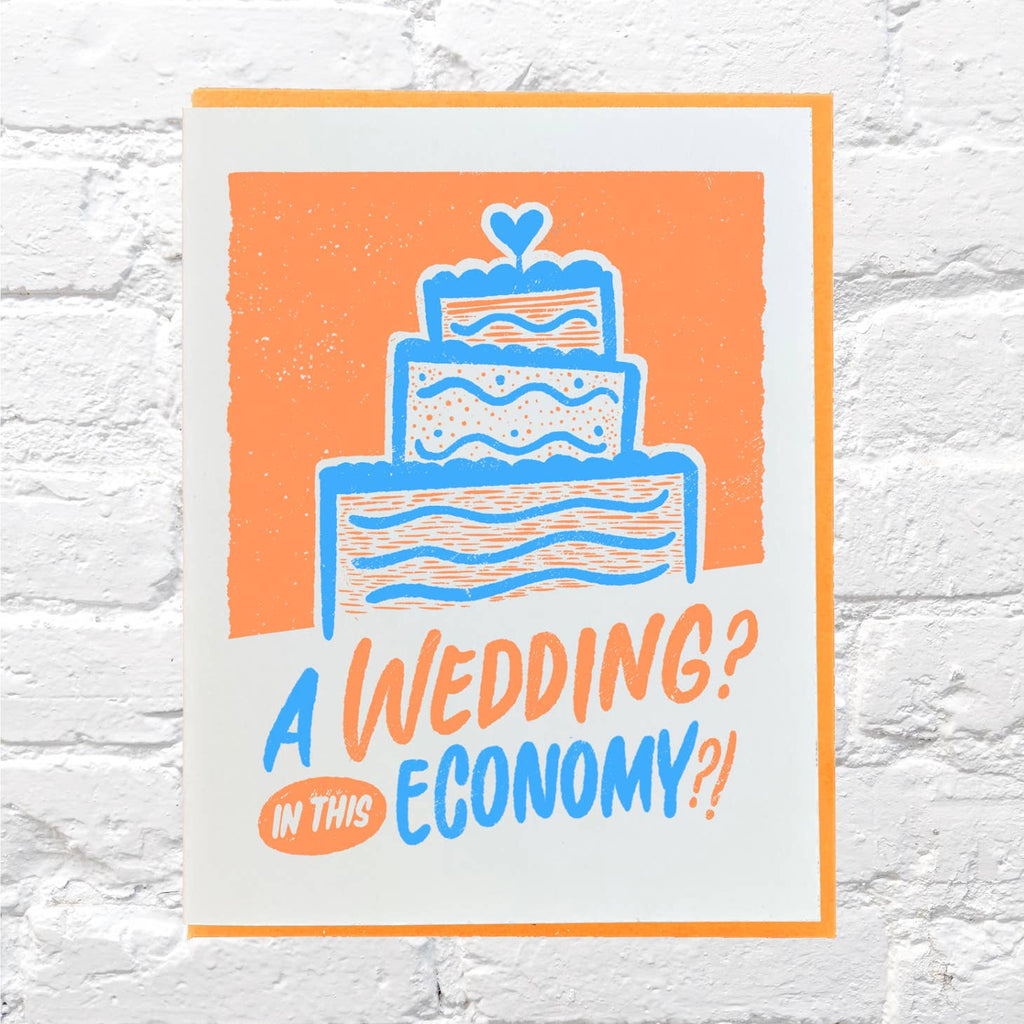 White background with image of blue, orange and white wedding cake. Blue and orange text says, "A wedding? In this economy?!". Kraft envelope is included.