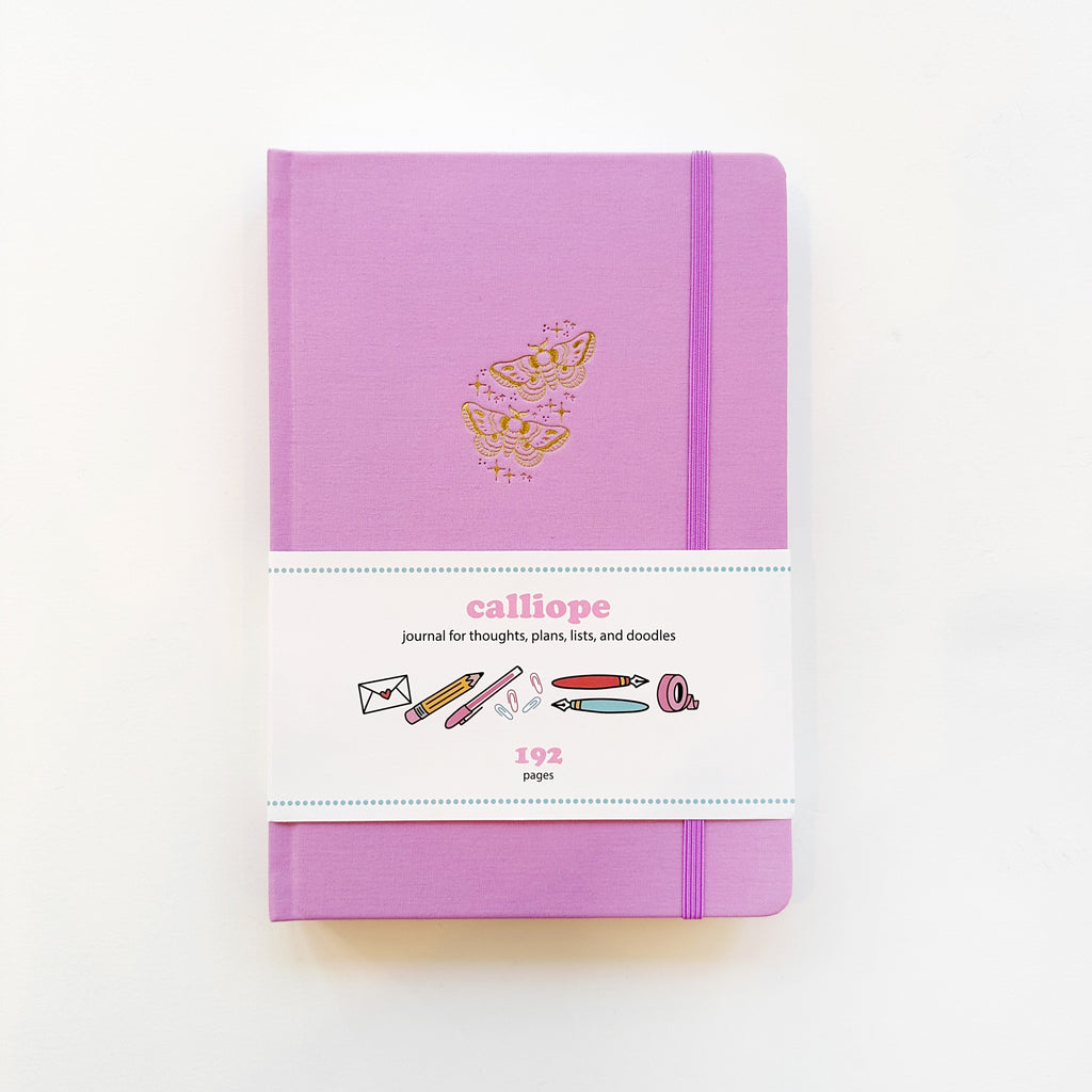 Image of lilac journal cover with gold foil moths with sparkles and elastic closure on right side of journal. 