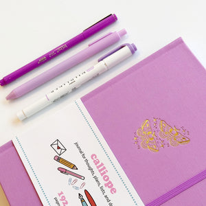 Image of lilac journal cover with gold foil moths with sparkles and elastic closure on right side of journal.