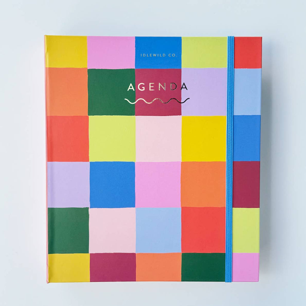 Cover of planner with rainbow colored checkered background with gold foil text says, "Agenda". 