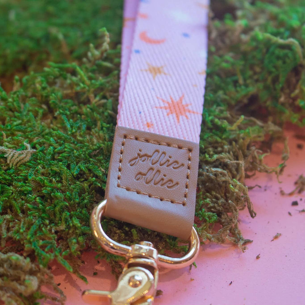 Pink background with orange moons and white stars with leather end and gold clip. 