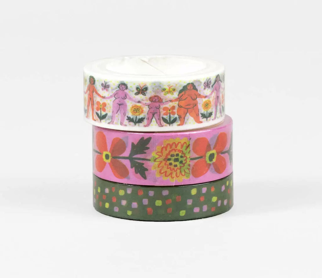 Three rolls of washi tape. One with cream background with images of naked women holding hands and flowers in orange, pink and green. Second is pink background with images of orange and yellow flowers. Thirs is green background with polka dots in neon green, pink and orange.