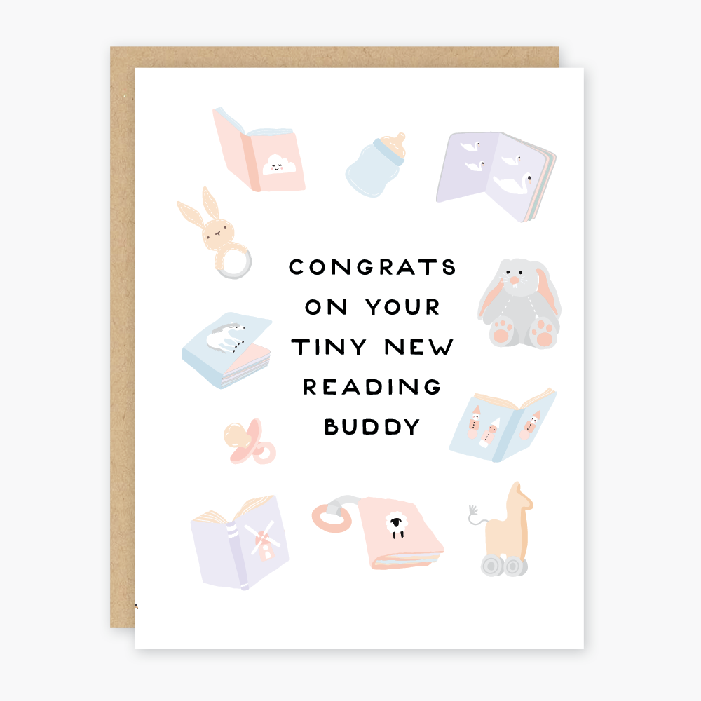 White card with black text saying, “Congrats On Your Tiny New Reading Buddy”. Images of baby items such as bottles, rattles, a bunny stuffed animal, books, and a pink rocking horse. A brown envelope is included. 