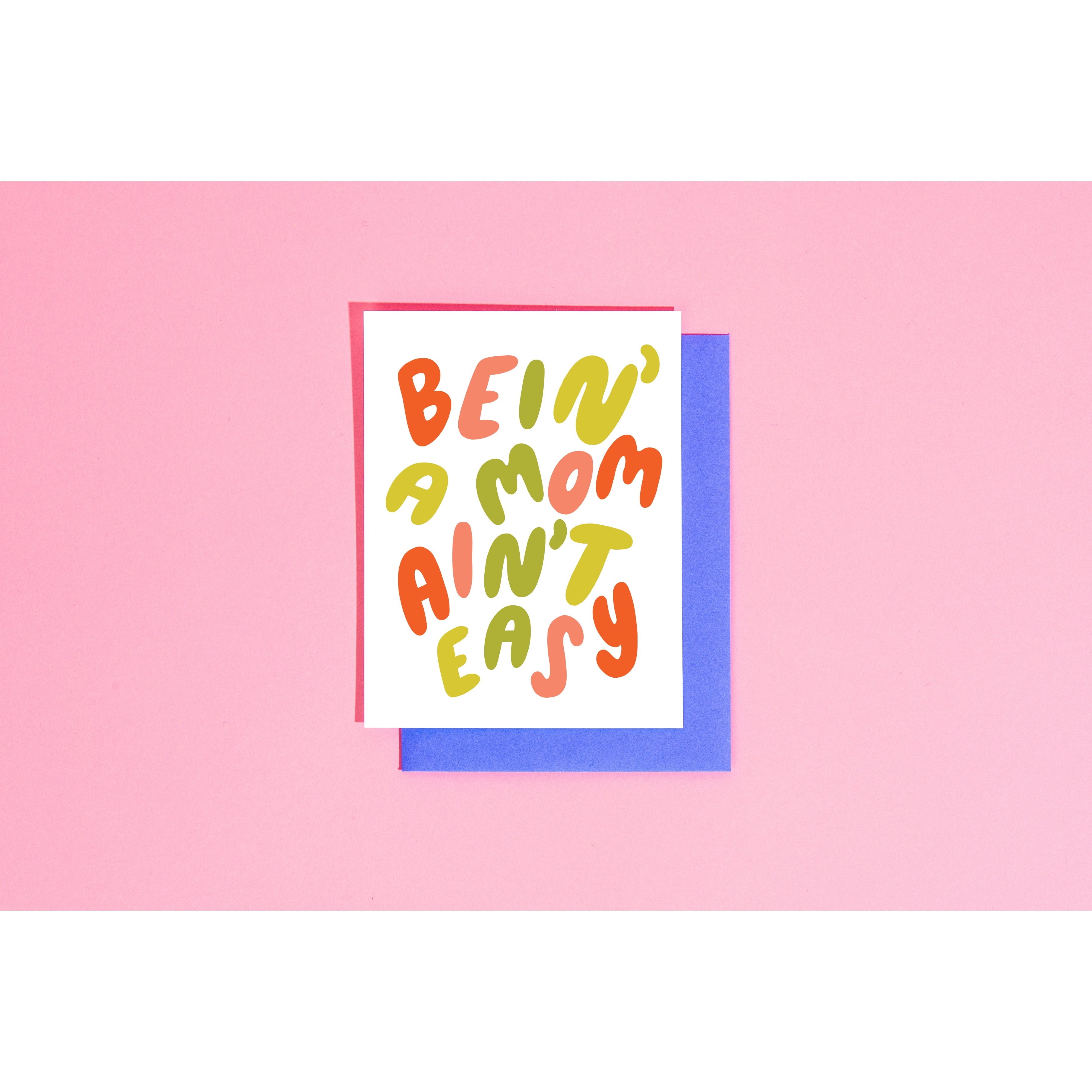 White card with red, pink and green text saying, “Bein’ A Mom Ain’t Easy”. A blue envelope is included.