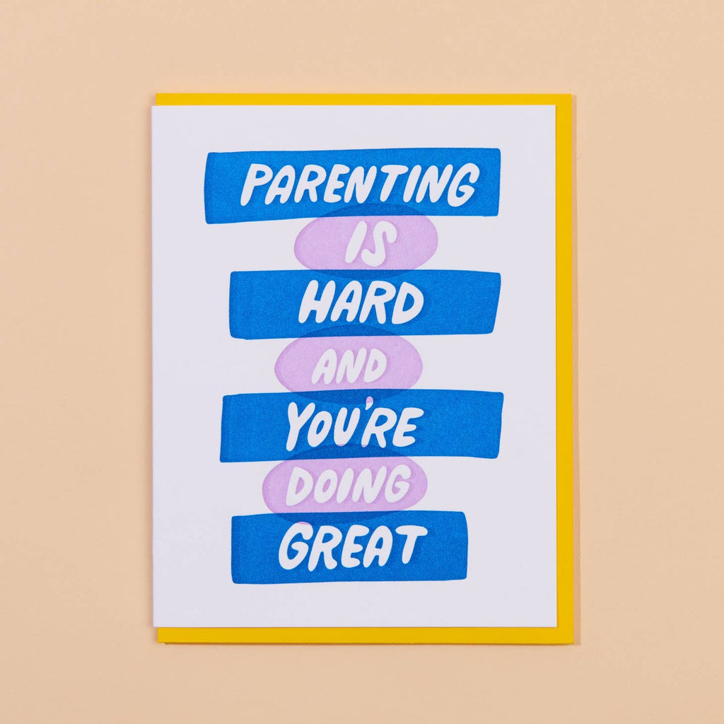 White card with white text in blue rectangles alternating with white text in lavender ovals that says “Parenting is hard and you’re doing great”. Bright yellow envelope included.            