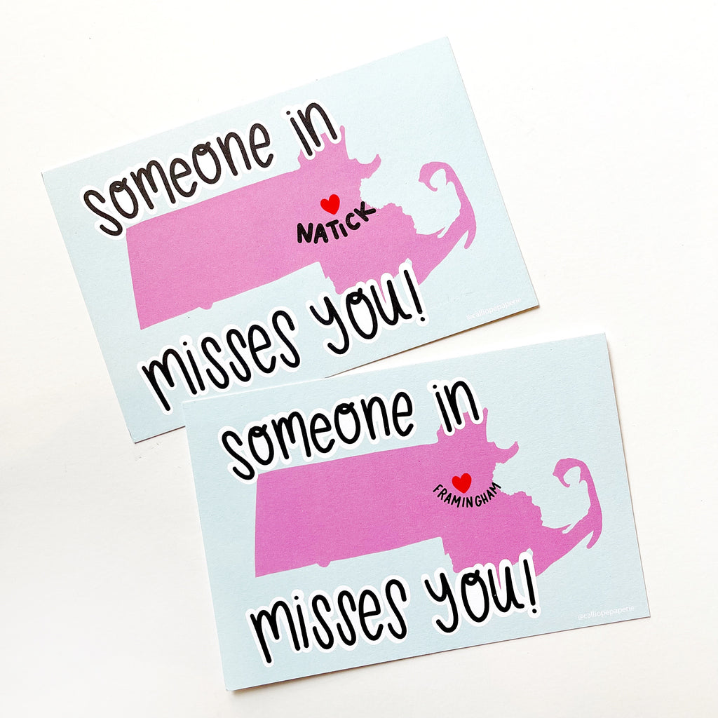 Image of two postcards with images of pink outline of state of Massachusetts with a red heart for Natick and one with red heart for Framingham. Black text says, "Someone in misses you!". 