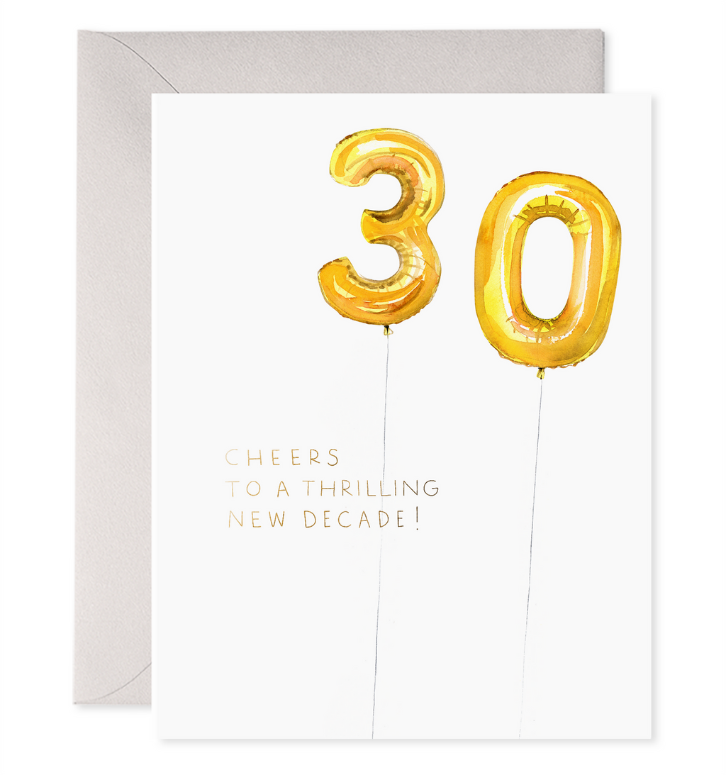 White card with black text saying, “Cheers to a Thrilling New Decade”. Images of gold foil balloons in the shape of a three and a zero. A purple envelope is included.