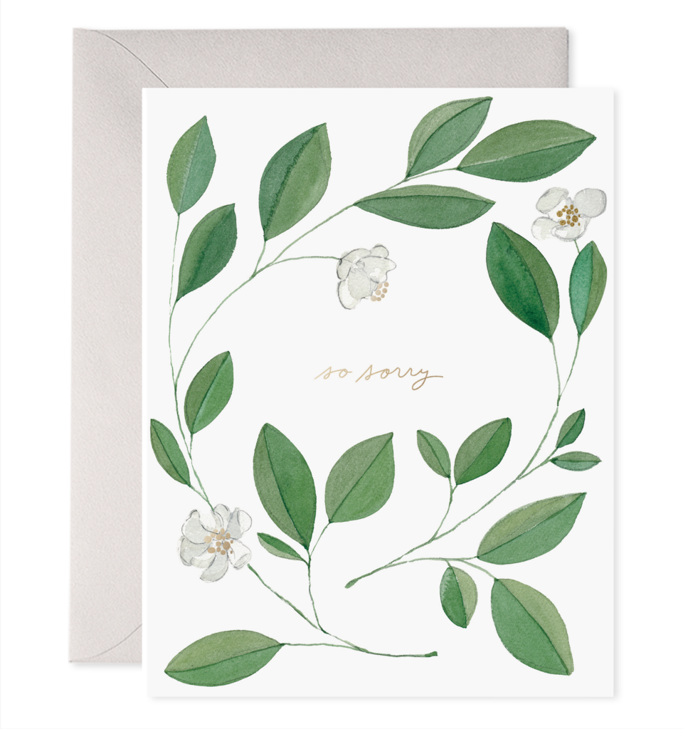 White card with gold text saying, “So Sorry”. Image of white flowers with greenery. A gray envelope is included.