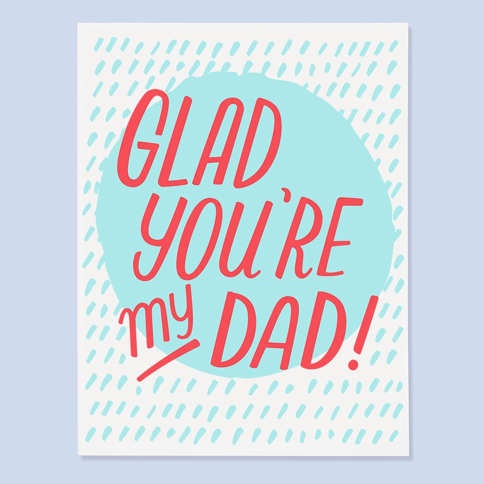 White card with red text saying, “Glad You’re My Dad”. Image of blue oval in middle of card with blue specks scattered on card. An envelope is included.