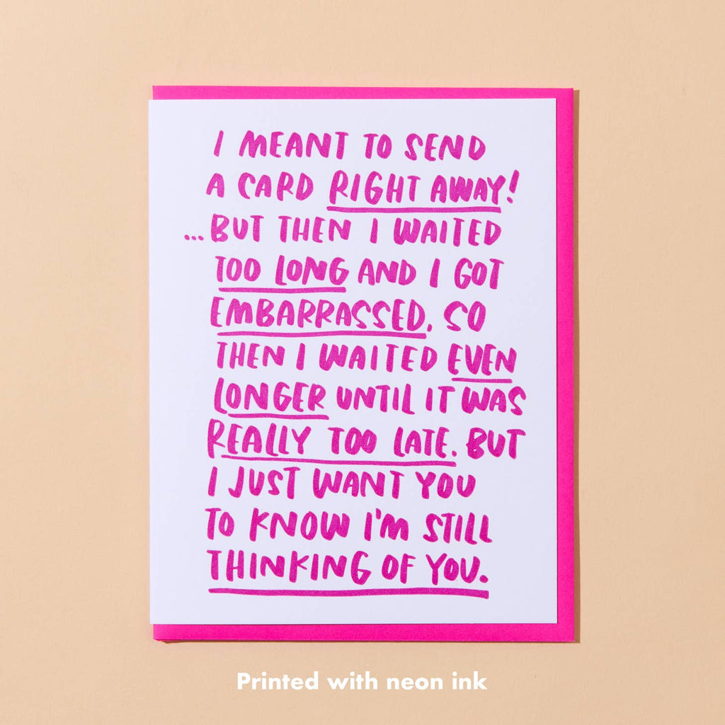 White card with neon pink text that says “I meant to send this card right away! But then I waited too long and I got embarrassed, so then I waited even longer until it was really too late. But I just want you to know I’m still thinking of you”. Neon pink envelope included.