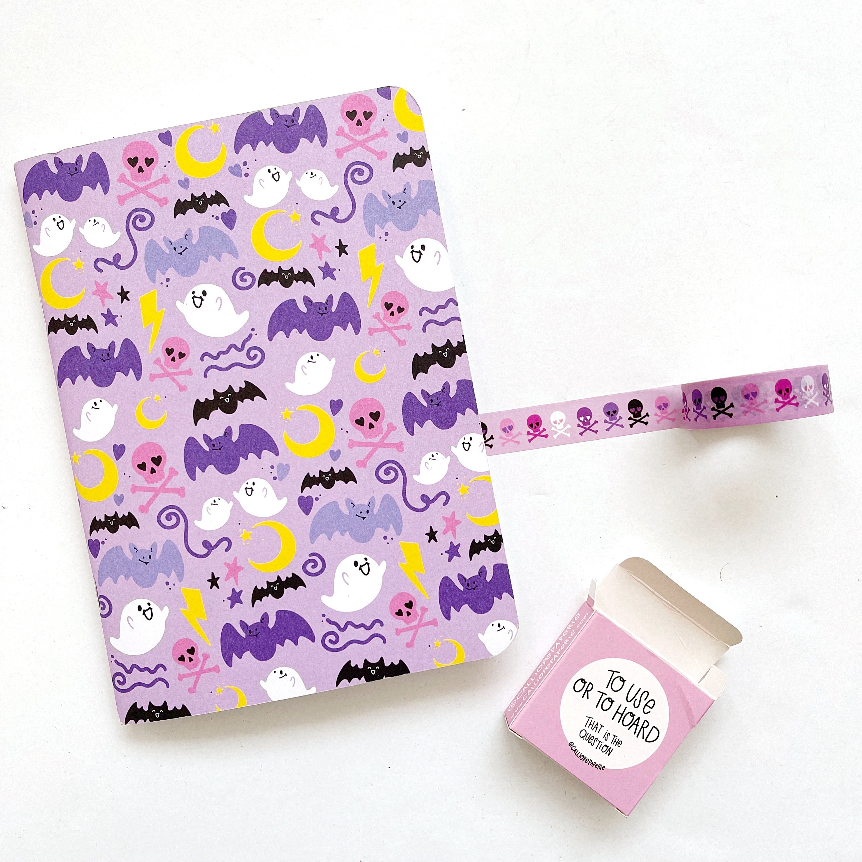 Image of notebook with lilac background and images of purple bats, white ghosts, yellow moons, pink skulls and black bats.