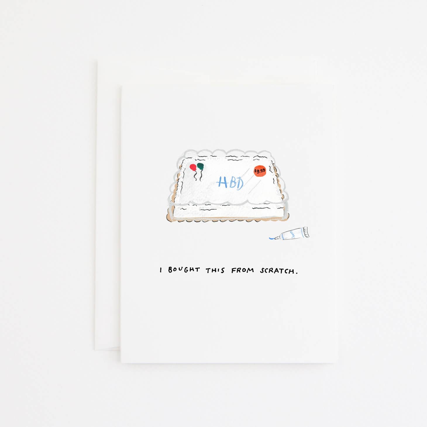 Greeting card with white background and image of a birthday sheet cake with blue frosting says, "HBD" and tube of blue frosting. Black text says, "I bought this from scratch." White envelope included. 