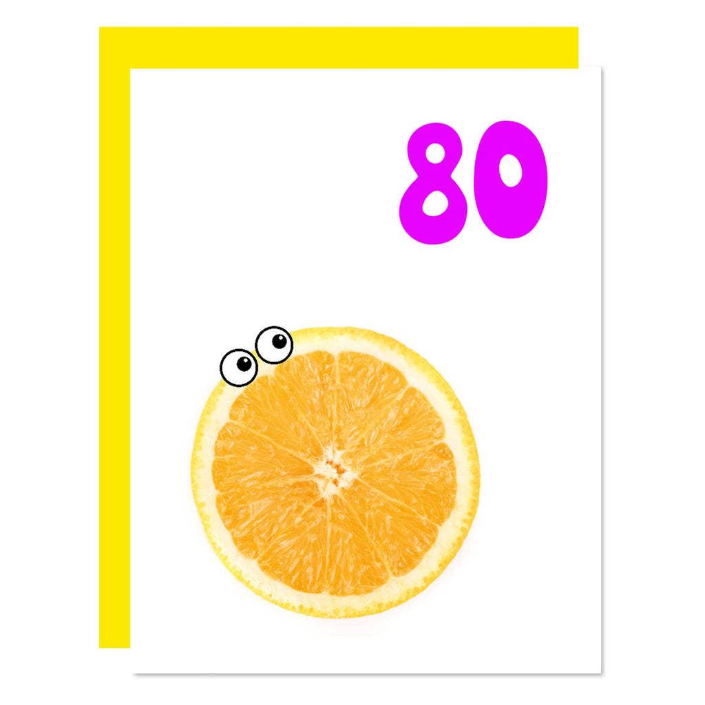 White background with image of sliced orange with eyes and hot pink :80". Yellow envelope included. 