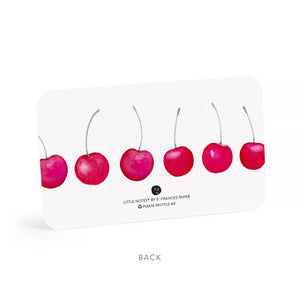 Back of tiny note with white background and images of red cherries lined up on card. 