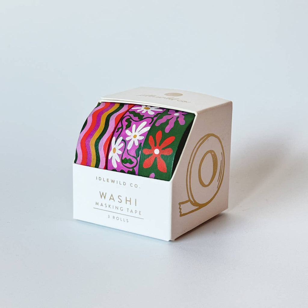 Image of set of three washi tapes in dark green, fushchia, red, white and gold. One is wavy stripes, one is white daisies on fuchsia background with green stems and leaves, and one is dark green background with red, fushia flowers with white centers. 