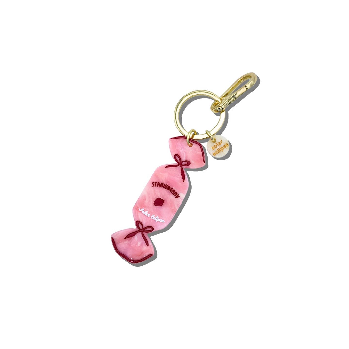 Image of keychain in shape of a piece of hard candy in pink, red and white with gold clip for keys. 