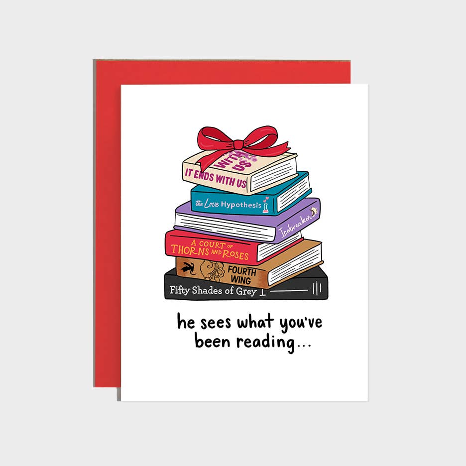 Greeting card with white background and image of stack of books with titles on bindings, "It ends with us, Love hypothesis, icebreaker, a court of thorns and roses, fourth wing, fifty shades of grey" and black text says, "he sees waht you've been reading...". Red envelope included. 