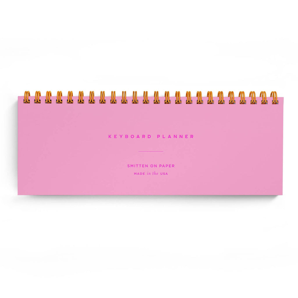 Planner with neon pink background and fuchsia text says, "Keyboard planner, Smitten on Paper, Made in the USA".  Gold coil binding on top. 