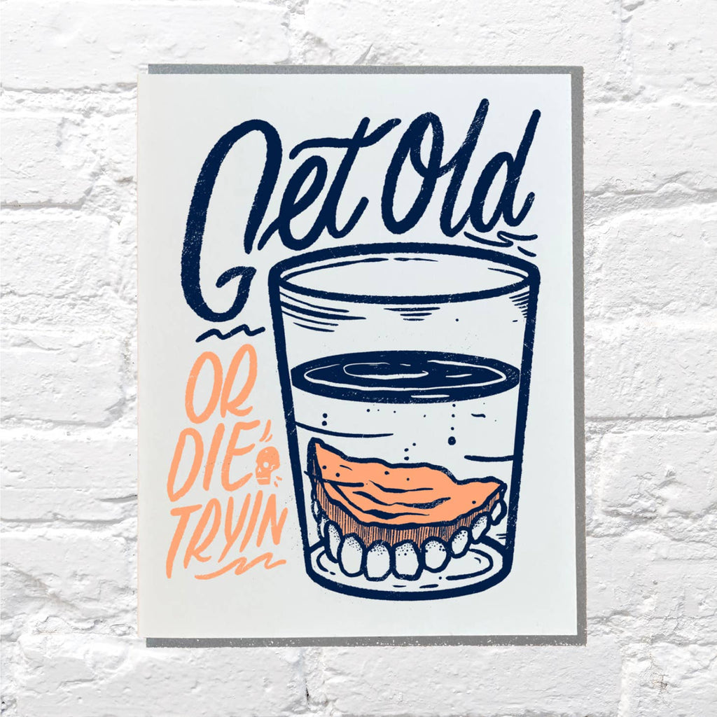 White background with image of dentures soaking in a glass with blue and orange text says, "Get old or die tryin"". Grey envelope included,.