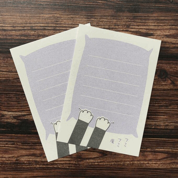 Small notepad with lilac background with white border and two black and white cat paws kneading a pillow.