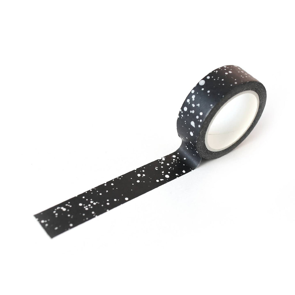 Image of roll of tape with black background with splatter design in silver. 