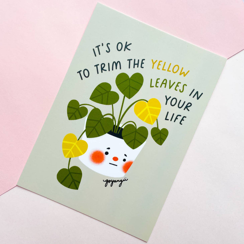 Pale green background with image of house plant with green and yellow leaves in white pot with sad face features. Black, yellow and green text says, “It’s ok to trim the yellow leaves in your life”.      