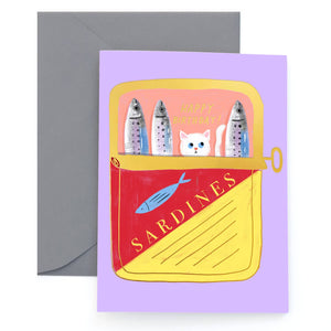 Greeting card with lavender background and image of yellow tinned fish with three fish and a kitty. Gold foil says, "Happy Birthday!" and yellow text says, "Sardines". Grey envelope included. 