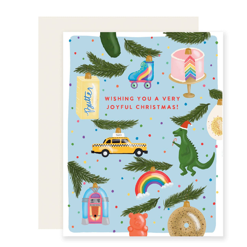 Box of greeting cards with blue background with images of ornaments including butter, roller skate, cake, dinosaur, bagel, rainbow and taxi with green boughs of pine. Envelope included. 