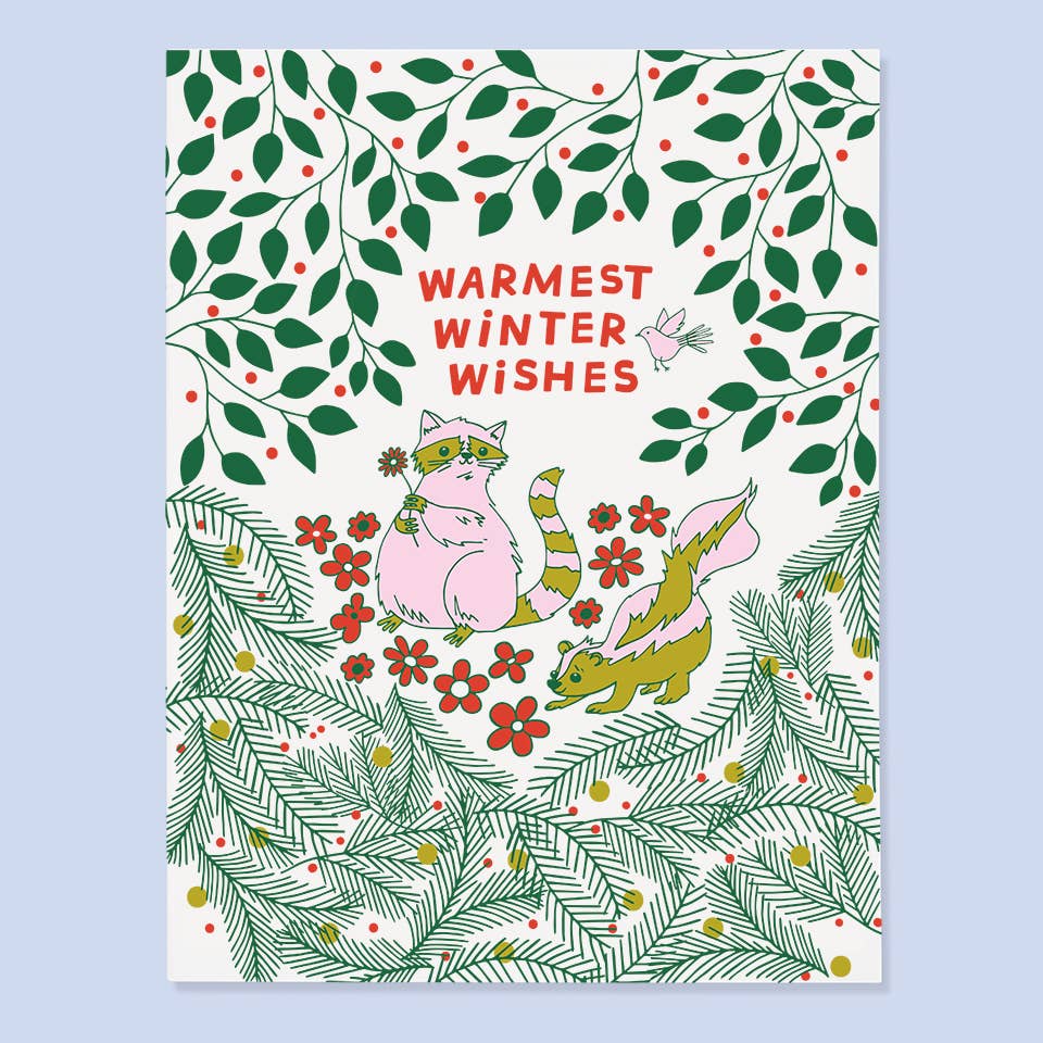 Greeting card with white background and pine branches on bottom of card and green vines with red berries on top of card. Image of a pink raccoon holding a flower and a skunk with red text says, "Warmest winter wishes". Envelope included.