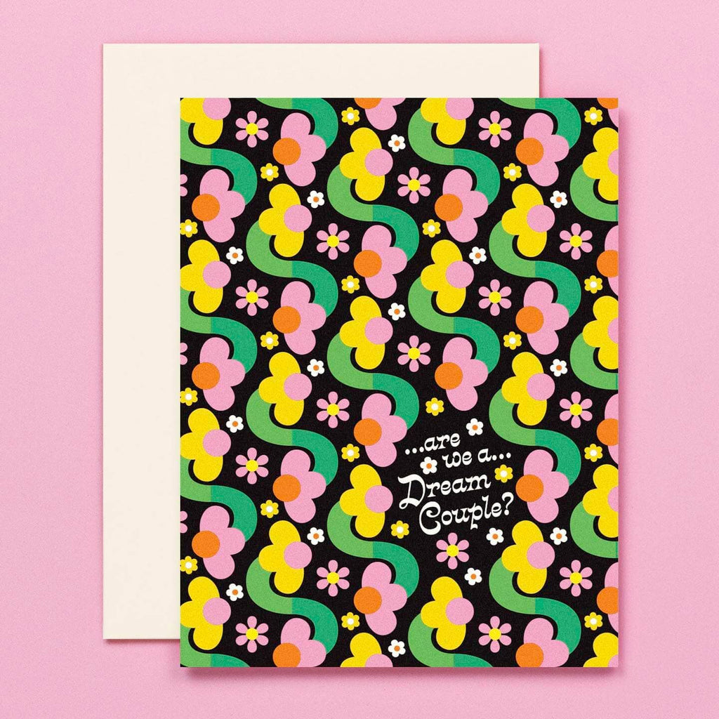 Greeting card with black background and images of pink and yellow flowers with green stems and white text says, "...are we a...dream couple?". White envelope included. 