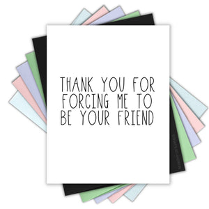 White background with black text says, “Thank you for forcing me to be your friend”. An envelope is included.             