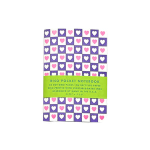 Notebook with purple and white checkered background with pink hearts in white checks and white hearts in purple checks. 
