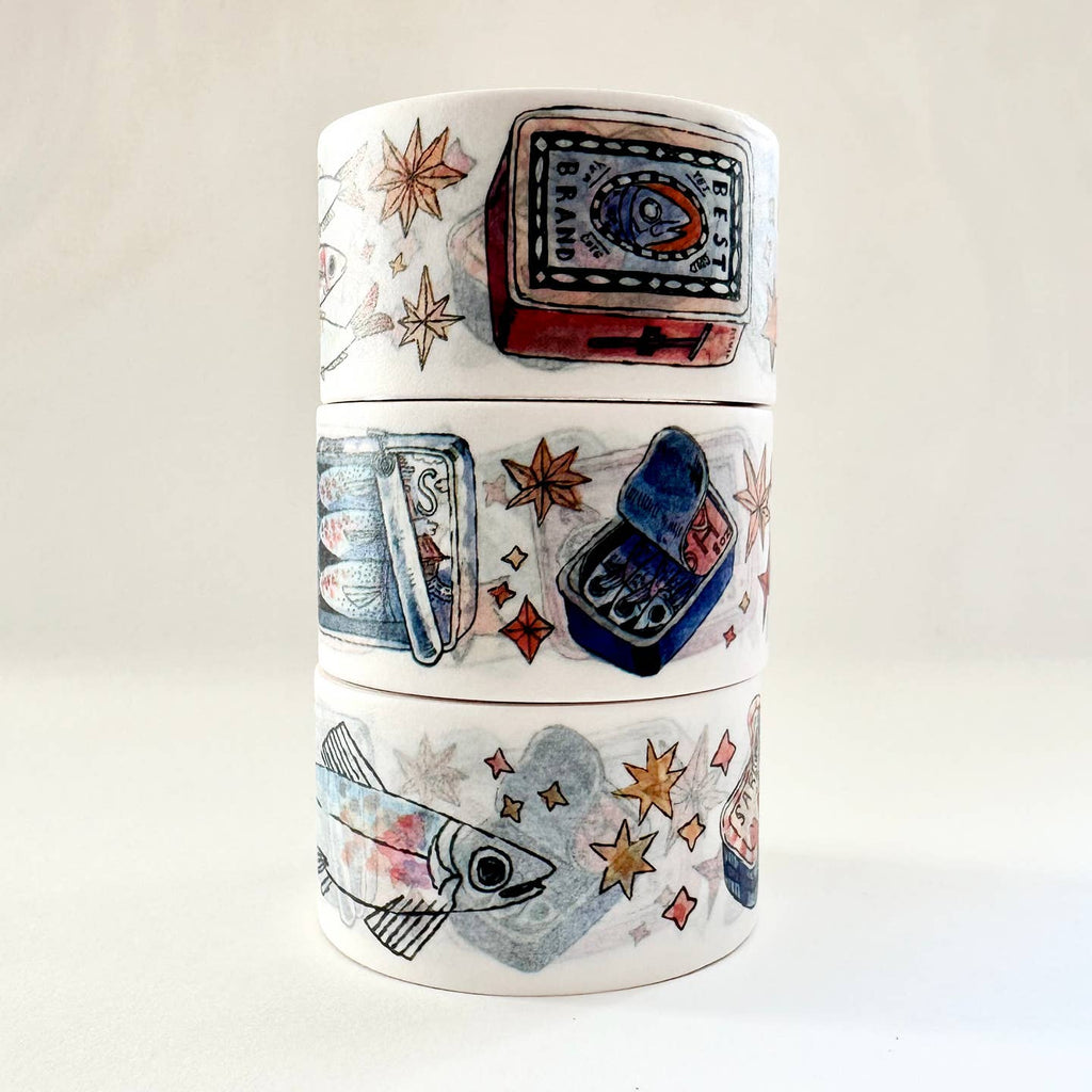 Image of washi tape with white background with images of sardines in cans and sardines in blues, orange and grey. 
