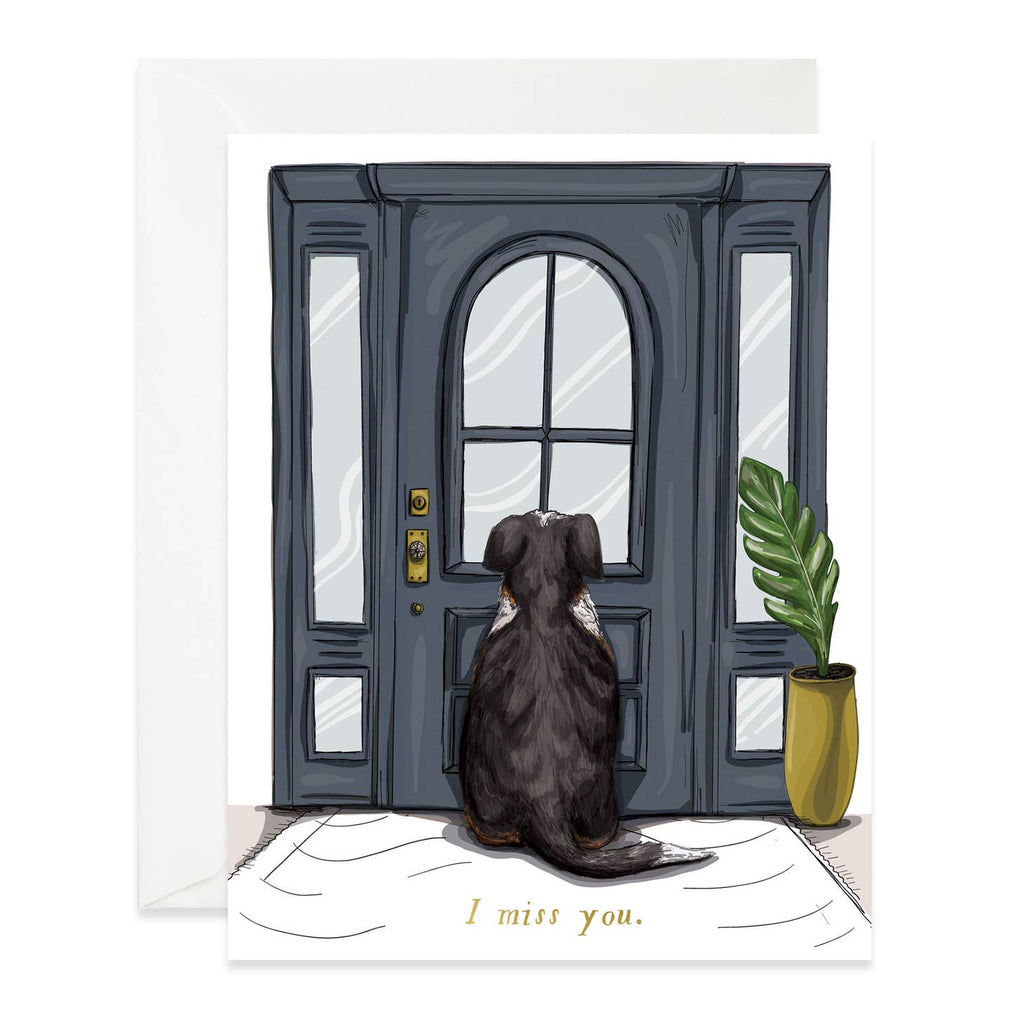White background with image of a black dog sitting and looking at a door. Gold text says, 'I miss you". White envelope included. 