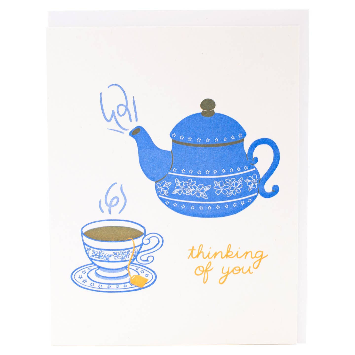 Greeting card with white background and image of blue teapot and blue and white cup and saucer of tea. Yellow text says, "thinking of you". Envelope included. 