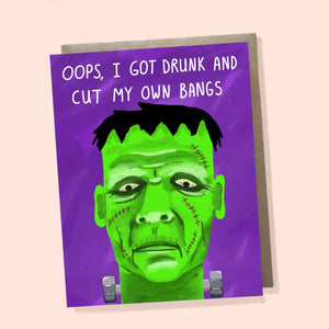 Greeting card with purple background with image of Frankenstein with green face and black hair. White text says, "Oops, I got drunk and cut my own bangs". Envelope included. 