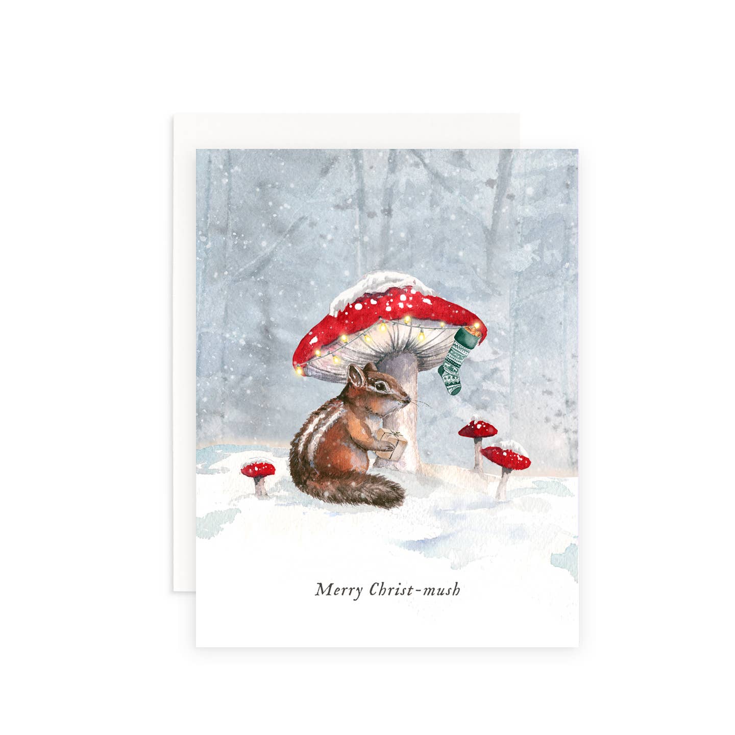 Greeting card with image of a chipmunk under a mushroom with a red cap and a stocking hanging off of it with a snowy forest background. Black text says, "Merry Christ-mush". White envelope included. 