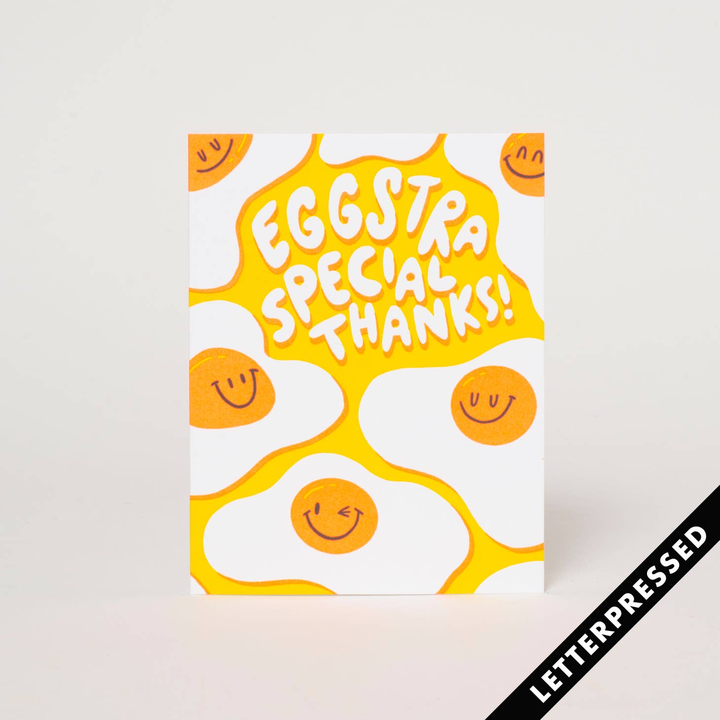 White background with images of fried eggs and white text says, "Eggstra special thanks!". Kraft envelope is included. 